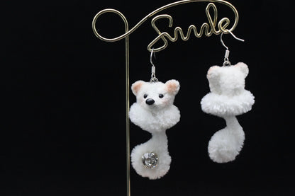 Handcrafted white wool twisted stick puppy earrings with light brown ears, subtle blush, and a sparkling gem on the curled tail, showing front and back details.