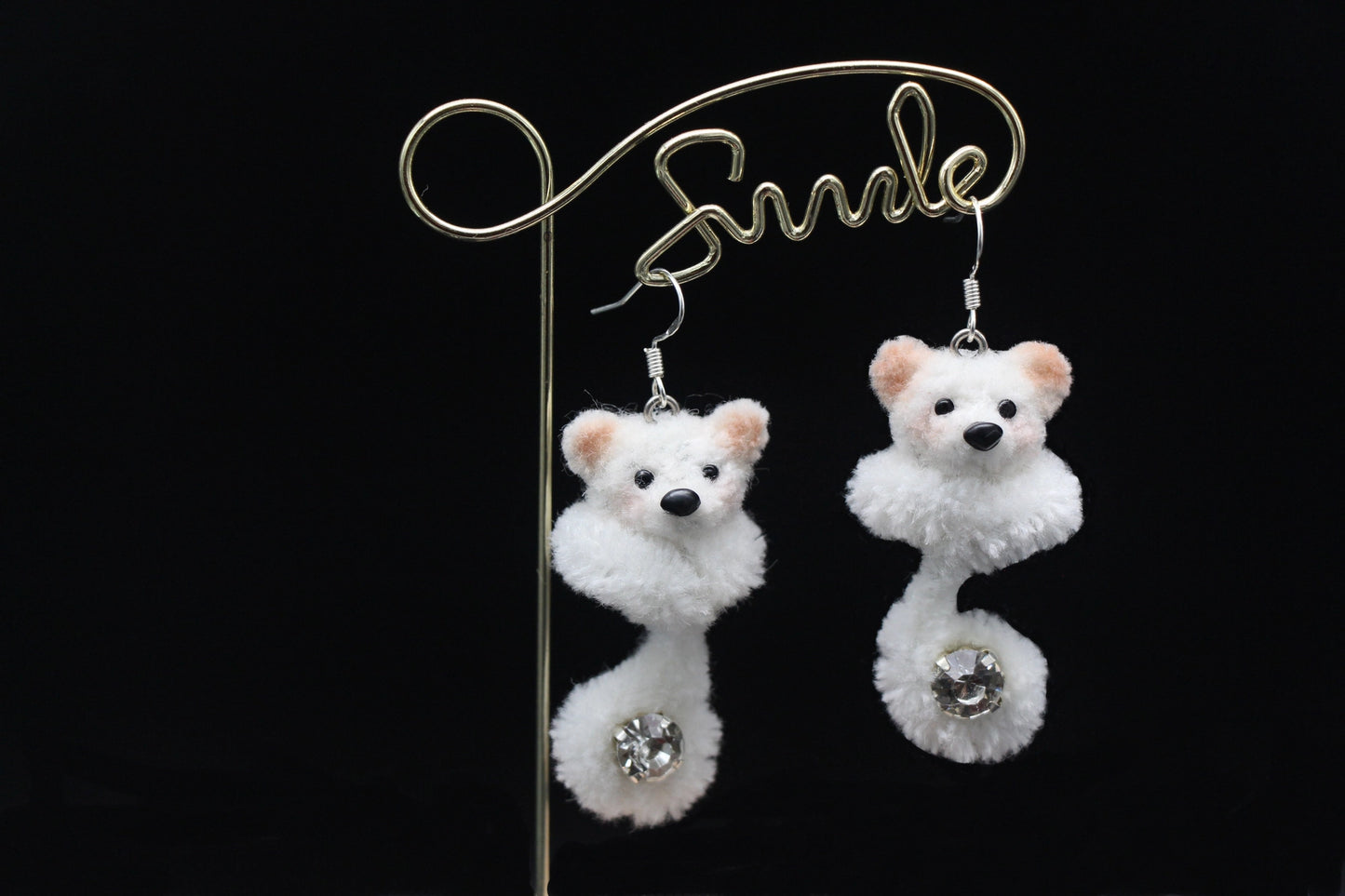 Handmade white wool twisted stick puppy earrings with light brown ears, subtle blush, and a sparkling gem on the curled tail, front view.