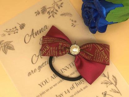 Handmade layered red hair tie with patterned & solid ribbons, central faux pearl accent on a black elastic band.